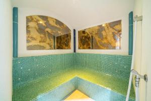 a bathroom with green tile and two paintings on the wall at Ferienhaus Maria Edelweiss in Pfelders