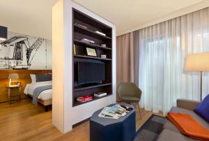 a living room with a bed and a tv in a room at Citadines Michel Hamburg in Hamburg