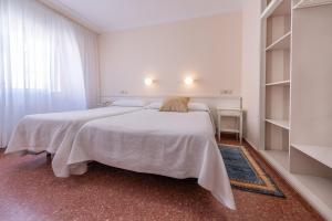 a white bedroom with two beds and a window at Hotel Minso in Sanxenxo