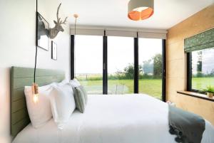 a bedroom with a large white bed with windows at Box6 at West Down in Sherborne