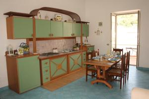 eine Küche mit grünen Schränken und einem Holztisch in der Unterkunft Casa della Conchiglia - Capri in Anacapri