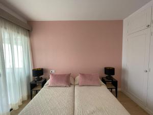 アロナにあるPlaya de las Vistas Los Cristianos WIFI BEACH VIEWのベッドルーム1室(ピンクの枕が付いた大型ベッド1台付)