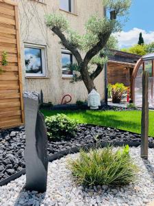 a garden with a tree in front of a house at Hôtel Restaurant Le Clos Fleuri in Castelnaudary