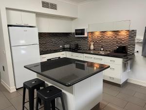a kitchen with white cabinets and a black counter top at Austral Place 88 via Merri River in Warrnambool