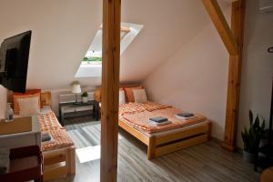 ein Dachzimmer mit zwei Betten und einem Fernseher in der Unterkunft Hostel 33 in Trzebinia