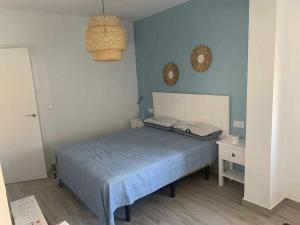 - une chambre avec un lit et un mur bleu dans l'établissement En la misma playa nuevo 3 dormit vistas al mar, à Punta Umbría