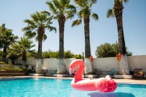a pink flamingo float in a swimming pool with palm trees at Myrto Hotel in Mati