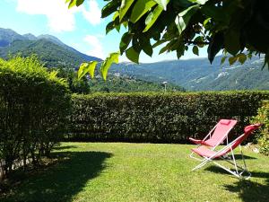 a pink chair sitting in the grass with mountains in the background at LA TAVERNETTA DEL RICCIO in Rota d'Imagna