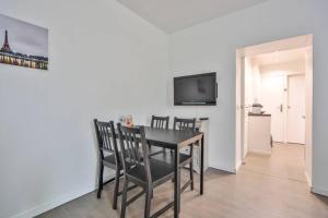 a dining room table with chairs and a television on a wall at Studio 4P Calme/Full Equipped/Charonne/PereLachese in Paris