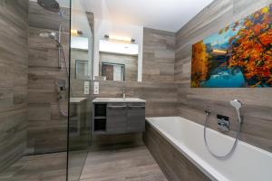 baño con bañera, lavabo y pintura en Boutiquehotel Strand Hallstatt - Adults only en Hallstatt