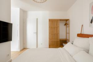 um quarto branco com uma cama e uma televisão em Sweet Suite - Zentrale Wohnung nähe Augarten em Viena