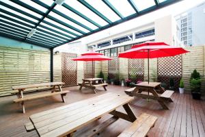 two picnic tables and red umbrellas on a deck at 24 Guesthouse Myeongdong Avenue in Seoul