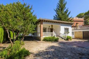 uma grande casa branca com um alpendre e árvores em Casa San Rafael amplio chalet con gran jardín em Navajas