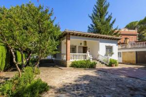 une grande maison blanche avec une véranda et des arbres dans l'établissement Casa San Rafael chalet con gran jardín, à Navajas