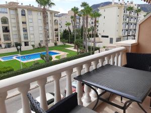 Un balcón con mesa y sillas y una piscina. en Primavera Sunshine, en Albir