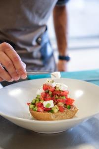 a person is eating a sandwich on a plate at Margo Beach Hotel in Gythio