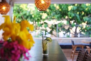 a table with a vase of flowers and a drink at Margo Beach Hotel in Gythio