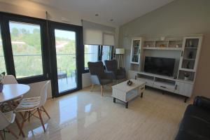 a living room with a television and a table and chairs at Santa Barbara Lakis Apartments in Perivólion