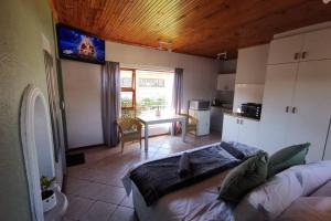 a living room with a bed and a kitchen at Cozy, peaceful garden cottage in Cape Town