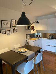 a kitchen with a dining room table with white cabinets at Pinzolo Wellness Apartment in Pinzolo