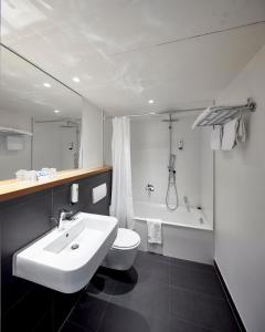 a bathroom with a sink and a toilet and a tub at Best Western Hotel Trier City in Trier +53 photos