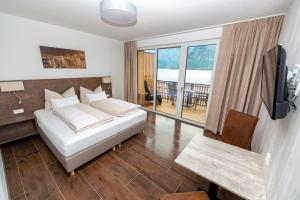 sypialnia z łóżkiem, telewizorem i stołem w obiekcie Boutiquehotel Strand Hallstatt - Adults only w Hallstatt