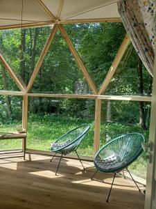 two chairs sitting in front of a large window at Młyn Hipolit glamping in Nowy Gaj