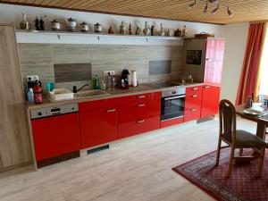 a kitchen with red cabinets and a table with a chair at Ferienwohnung Zur Glewe in Neustadt-Glewe