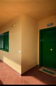 Habitación con puerta verde y suelo de baldosa. en Quinta Azul en Santa Úrsula