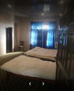 2 camas en una habitación con cortinas azules en Happy Heart Hotel & Restaurant, en Malam Jabba