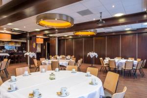 une salle à manger avec des tables et des chaises blanches dans l'établissement Fletcher Hotel-Restaurant Arneville-Middelburg, à Middelbourg