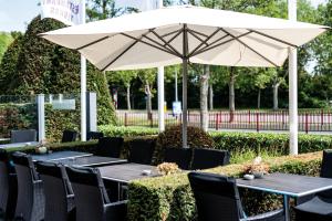 een tafel met een witte parasol en zwarte stoelen bij Fletcher Hotel-Restaurant Arneville-Middelburg in Middelburg