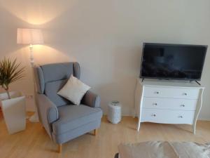 een woonkamer met een stoel en een flatscreen-tv bij Muemling Apartment 2 in Erbach