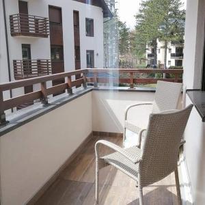 2 sillas sentadas en el balcón de un edificio en Apartman & Spa Pino Dorado Zlatibor, en Zlatibor