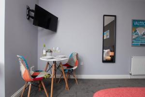 a dining room with a table and chairs and a tv at Delven House, Apartment 2 in Castle Donington