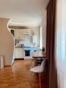 een keuken met witte kasten en een tafel en stoelen bij Apartment Sobornyi Prospect 95 in Zaporozhye