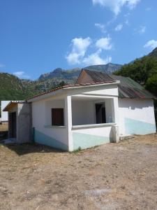 mały biały dom z górami w tle w obiekcie Vikendica w mieście Čanj