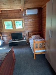 Dormitorio con cama y escritorio en una cabaña de madera en Vikendica, en Čanj