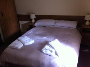 a bedroom with a large white bed with towels on it at The Stables - 200 Year Old Stone Built Cottage in Foxford