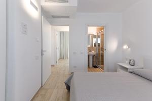 a white bedroom with a bed and a bathroom at Capo Falcone Charming Apartments in Stintino