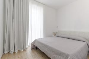 a white bedroom with a bed and a window at Capo Falcone Charming Apartments in Stintino