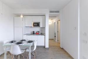 a white kitchen with a table and white chairs at Capo Falcone Charming Apartments in Stintino