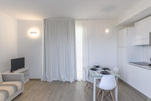 a white living room with a table and a couch at Capo Falcone Charming Apartments in Stintino