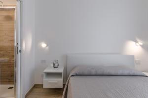 a white bedroom with a bed and a white nightstand at Capo Falcone Charming Apartments in Stintino