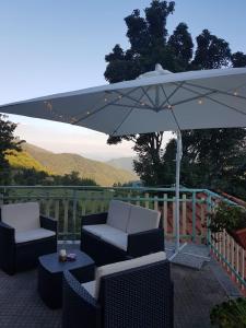 a patio with two chairs and an umbrella at Locanda Belvedere Pey in Zerba