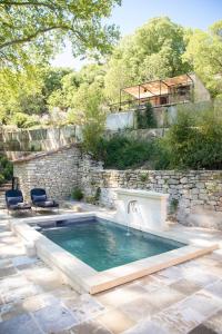 een zwembad met een waterval en een stenen muur bij Les Cabanes de la Fontaine in Lacoste