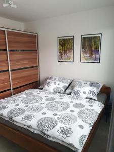 a bed with black and white sheets and pillows at Family apartmán Kovářská in Kovářská