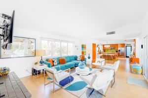 ein Wohnzimmer mit einem blauen Sofa und weißen Stühlen in der Unterkunft Casa Mesa Permit# 2665 in Palm Springs