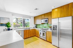 una cocina con armarios de madera y electrodomésticos de acero inoxidable en Casa Mesa Permit# 2665, en Palm Springs