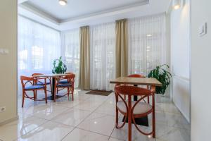 a dining room with two tables and chairs and windows at Villa Marina Inn in Siófok